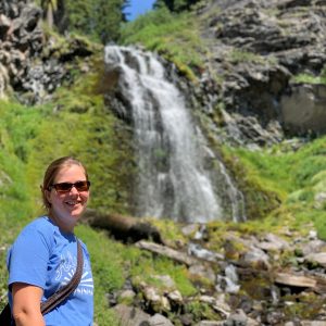 woman smiling at camera with waterfall in background